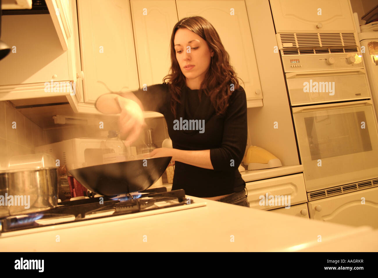 Weiblich, Kochen mit Wok auf Gas-Kochfeld Stockfoto