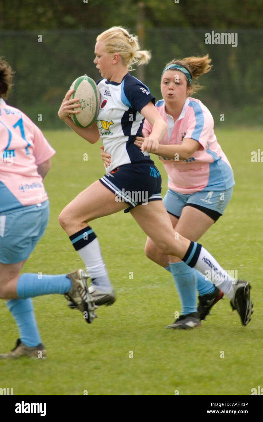junge Frauen spielen Rugby Aberystwyth Universität - Mädchen aus einem Zweikampf mit dem Ball in der Nähe ihrer Brust versteckt sprinten Stockfoto