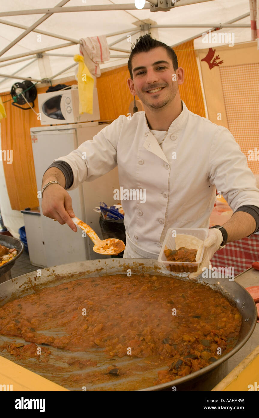 Lächelnde junge männliche französische Kochen bereitet einen großen Topf mit frischen warmen Speisen auf einem Marktstand in Aberystwyth Ceredigion Wales UK Stockfoto