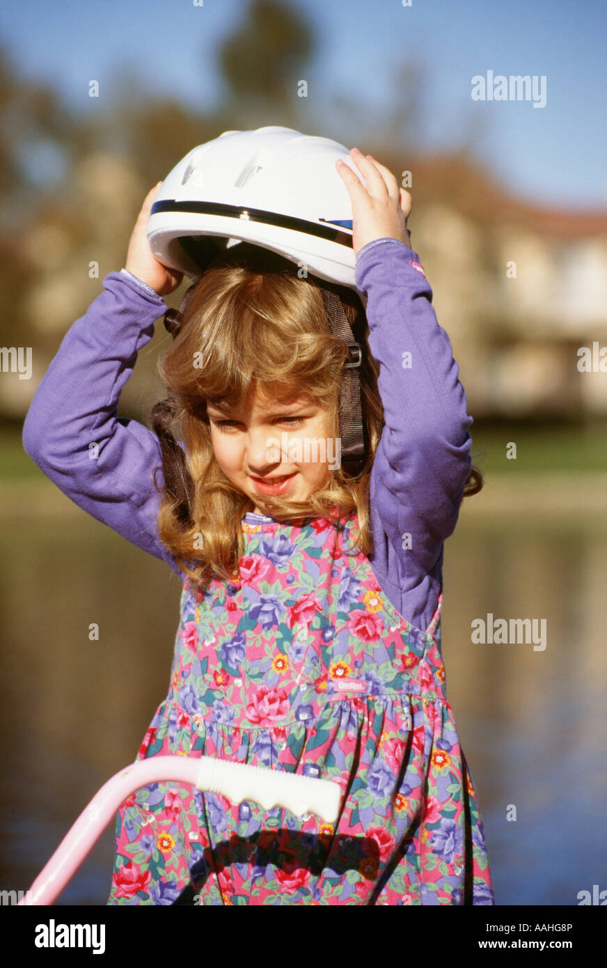 Junge Mädchen 4 -6 Jahre alten Holding putting Fahrrad Helm auf dem Kopf sitzen auf dem Fahrrad Aktivität US USA United States. Herr © Myrleen Pearson ....... Ferguson Cate Stockfoto