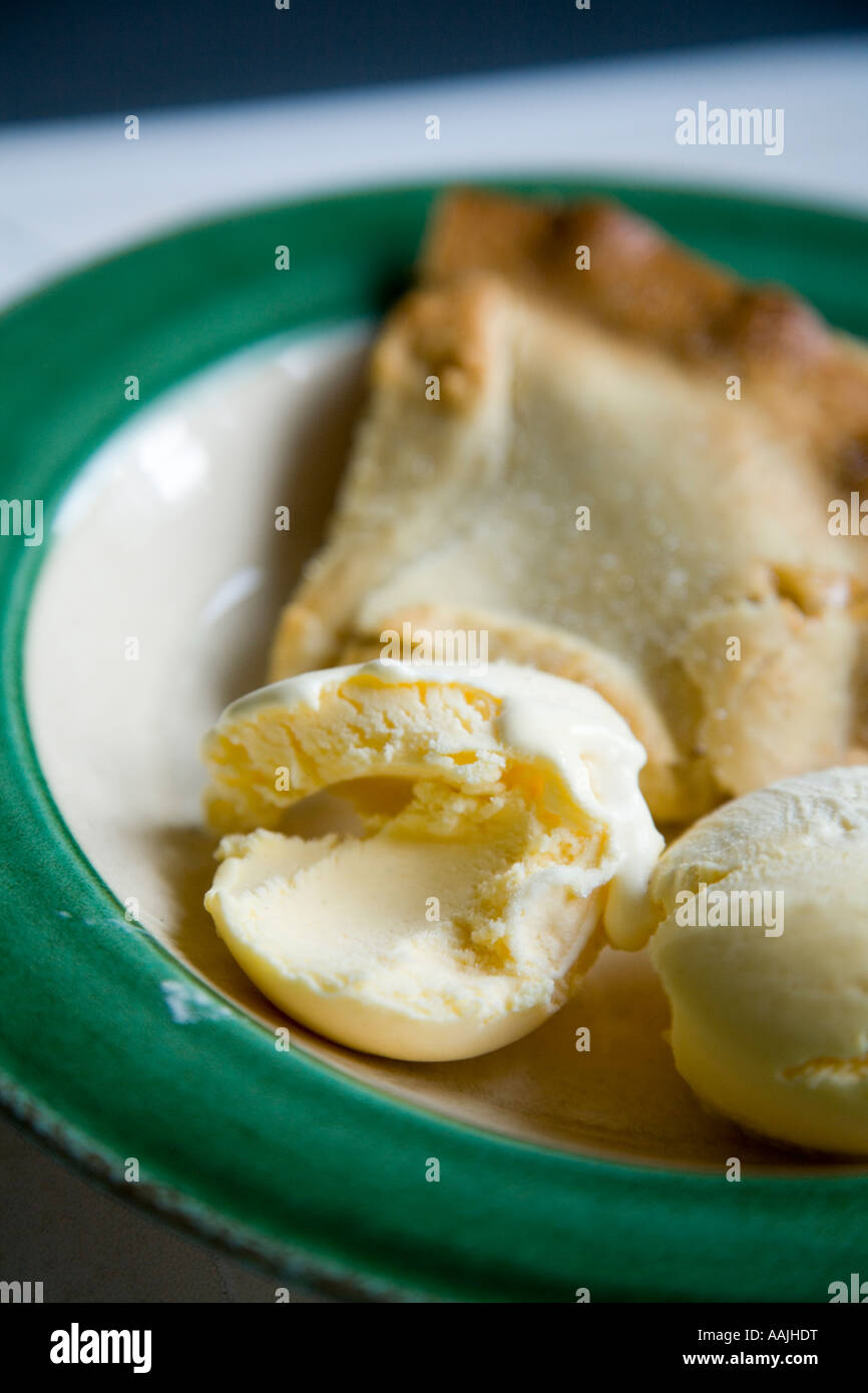 Nahaufnahme von Apfelkuchen und Vanille-Eis in einer grünen und weißen Schale auf eine weiße Küchenarbeitsplatte Stockfoto