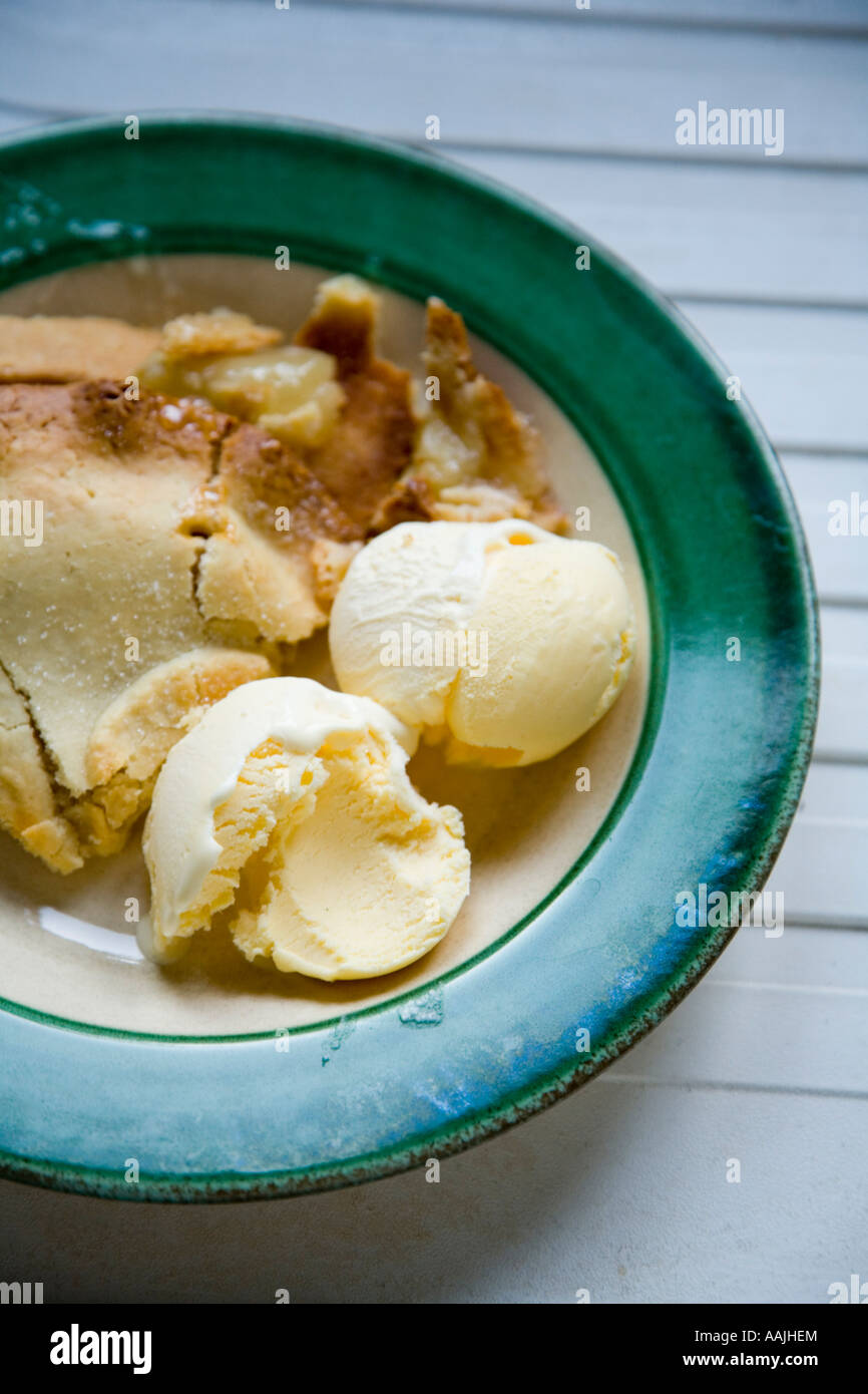 Nahaufnahme von Apfelkuchen und Vanille-Eis in einer grünen und weißen Schale auf eine weiße Küchenarbeitsplatte Stockfoto