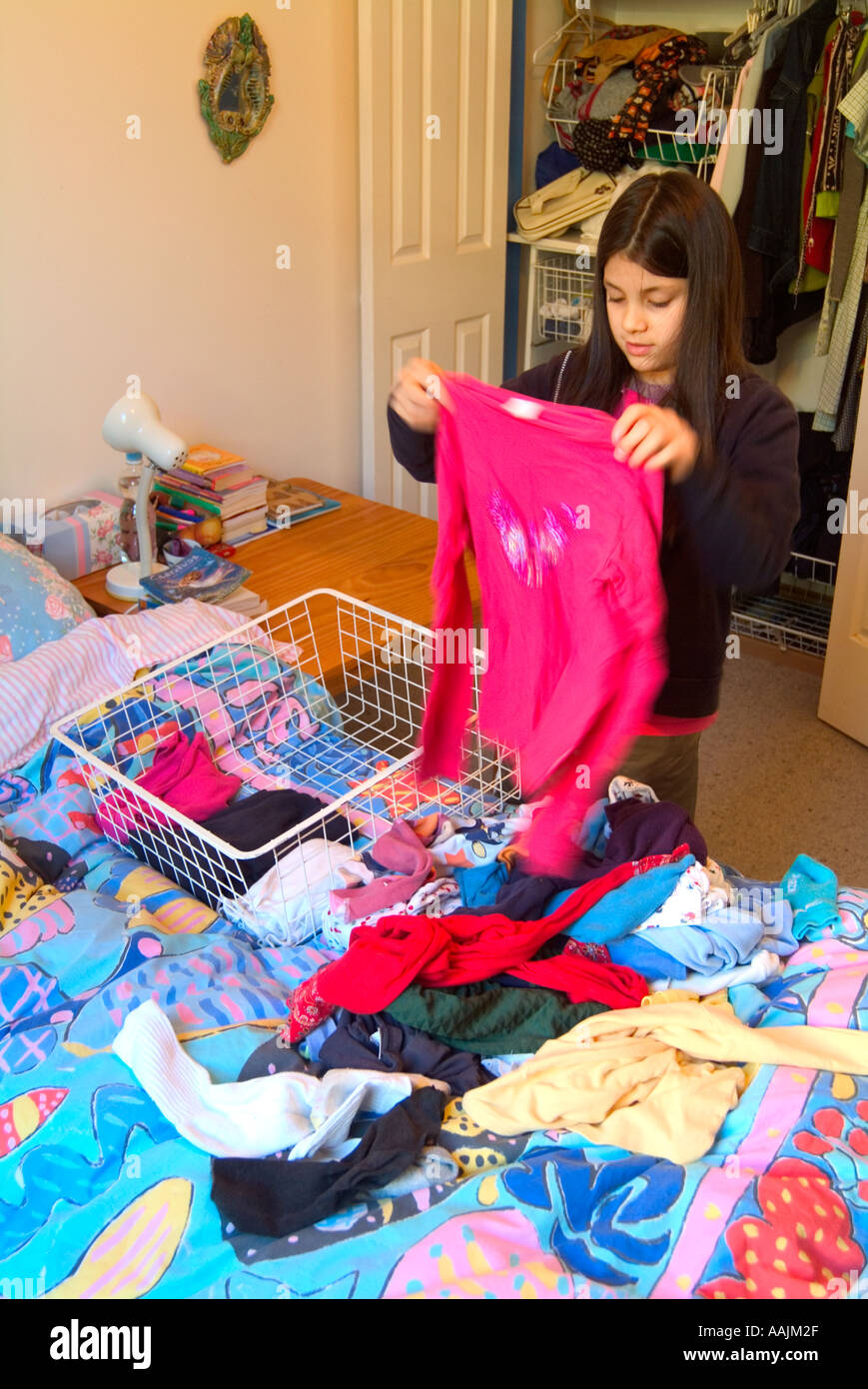 Ein Junge 9 Jahres altes Mädchen aufräumt, ihre Garderobe Stockfoto