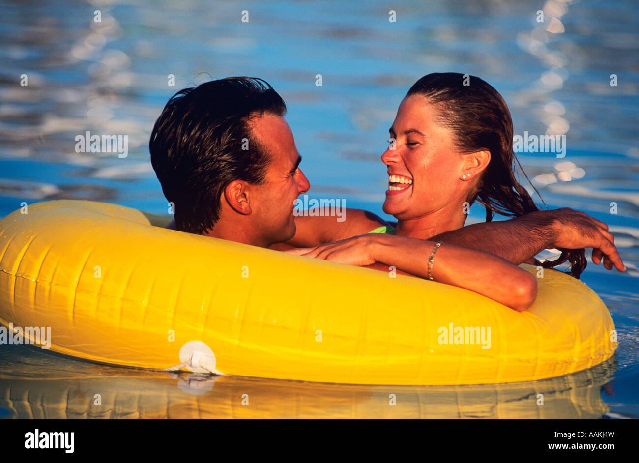 1980ER JAHRE JUNGE BRAUTPAAR SCHWEBEN IM INNEREN KUNSTSTOFFROHR IM POOL Stockfoto