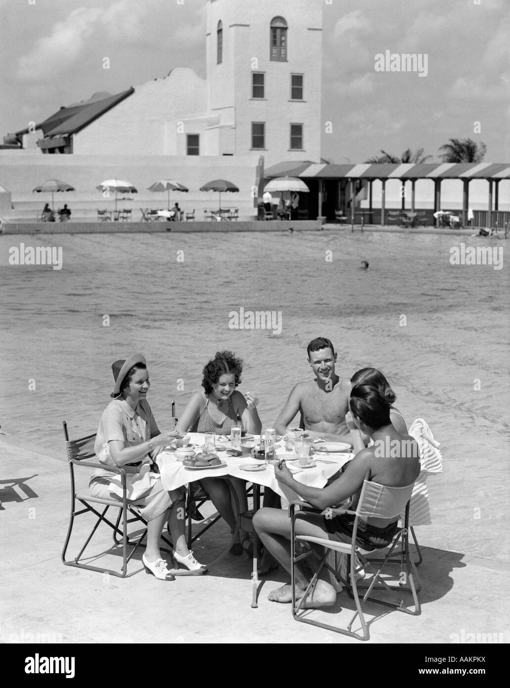 1930ER JAHRE GRUPPE 5 MÄNNER FRAUEN ESSEN POOL POOL TISCH URLAUB HOTEL REISEN ESSEN MIAMI FLORIDA Stockfoto
