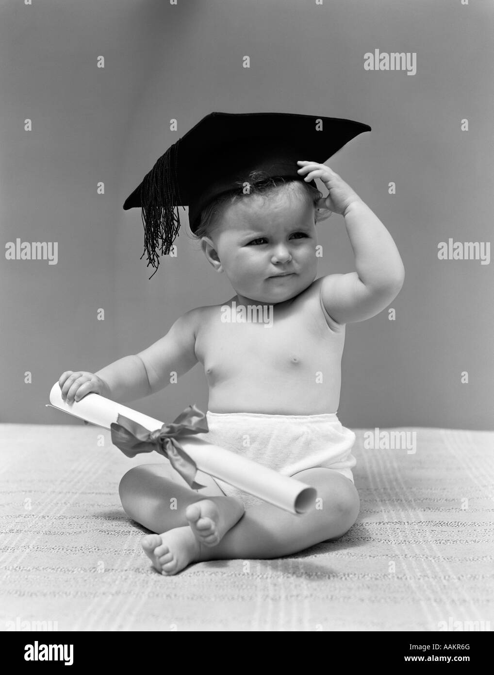1940ER JAHRE BABY TRAGEN MÖRSER BOARD GRADUATION CAP UND HOLDING-DIPLOM Stockfoto