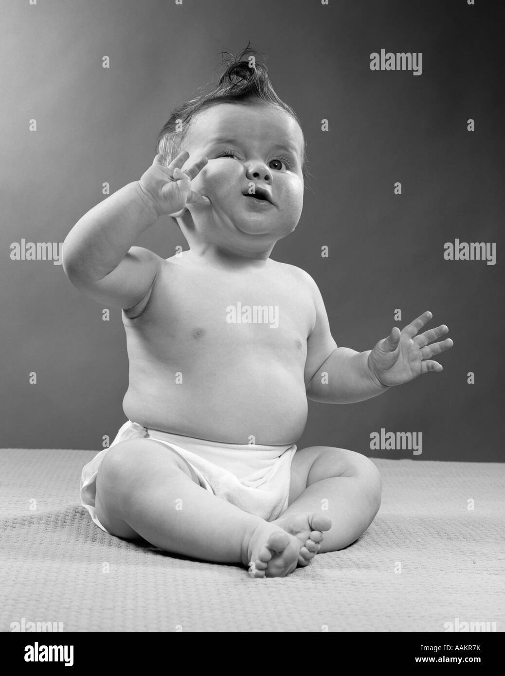 1950ER JAHREN GANZER FIGUR BABY SITTING GESTE DER HAND BERÜHREN WANGE GESICHTSAUSDRUCK LUSTIG Stockfoto