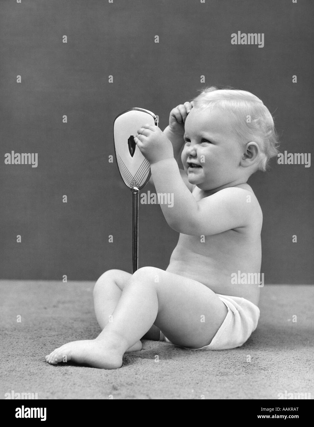 1940ER JAHRE BLONDE BABY GIRL HOLDING KOSMETIKSPIEGEL BLICK AUF IHR HAAR Stockfoto