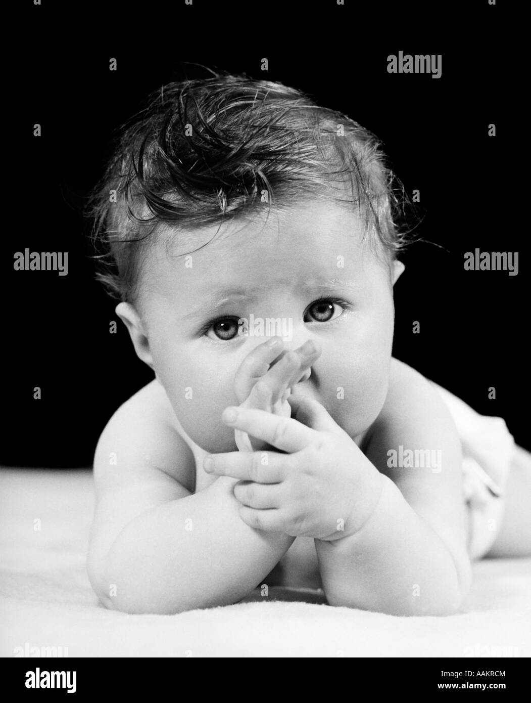 1940ER JAHRE NIEDLICHE BABY SAUGEN DAUMEN BLICK IN DIE KAMERA Stockfoto