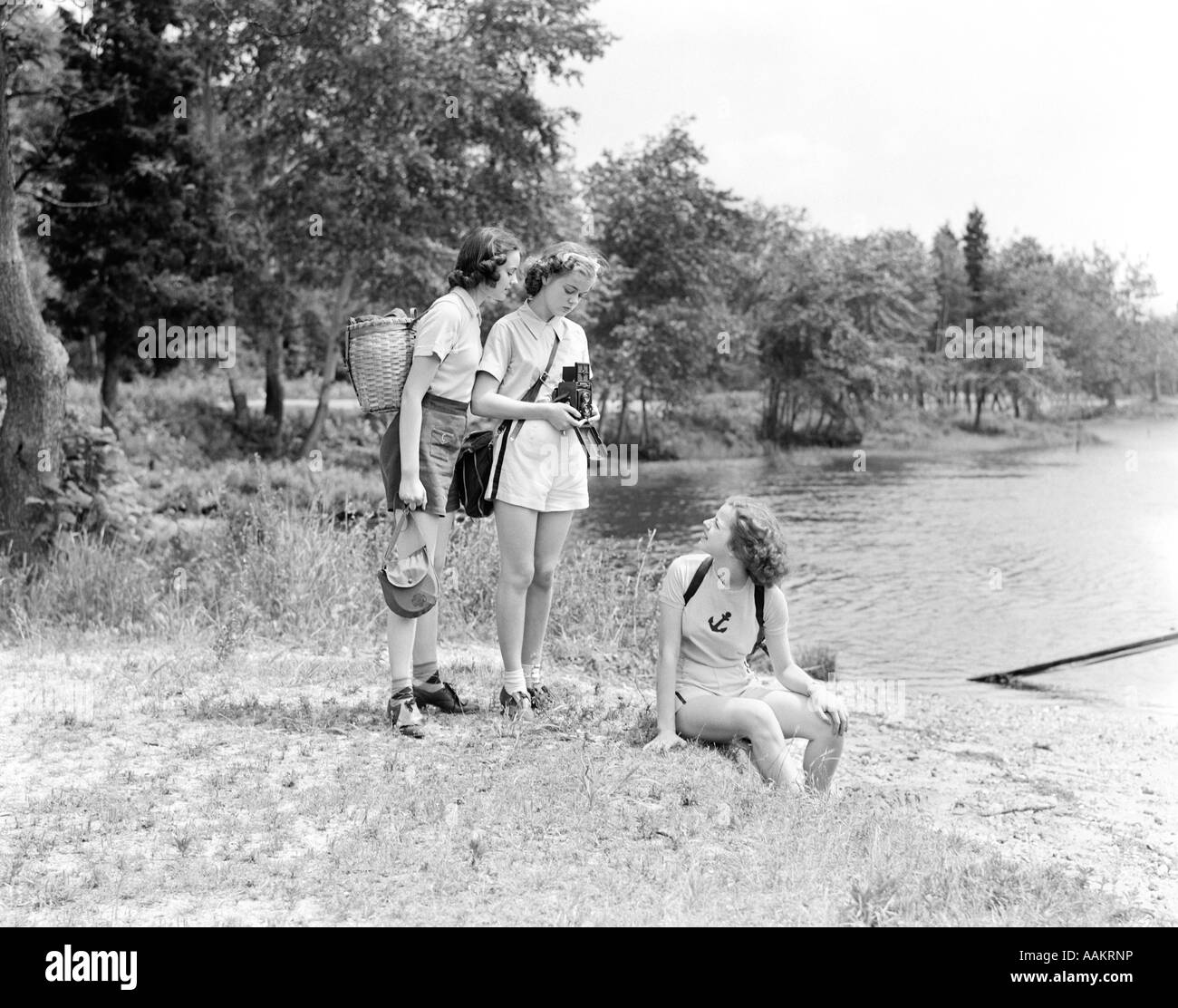 DREI JUNGE DAMEN FRAUEN WALD SEE SITZEN NATURFOTOGRAFIE KAMERA FOTOGRAF-1940ER JAHRE Stockfoto