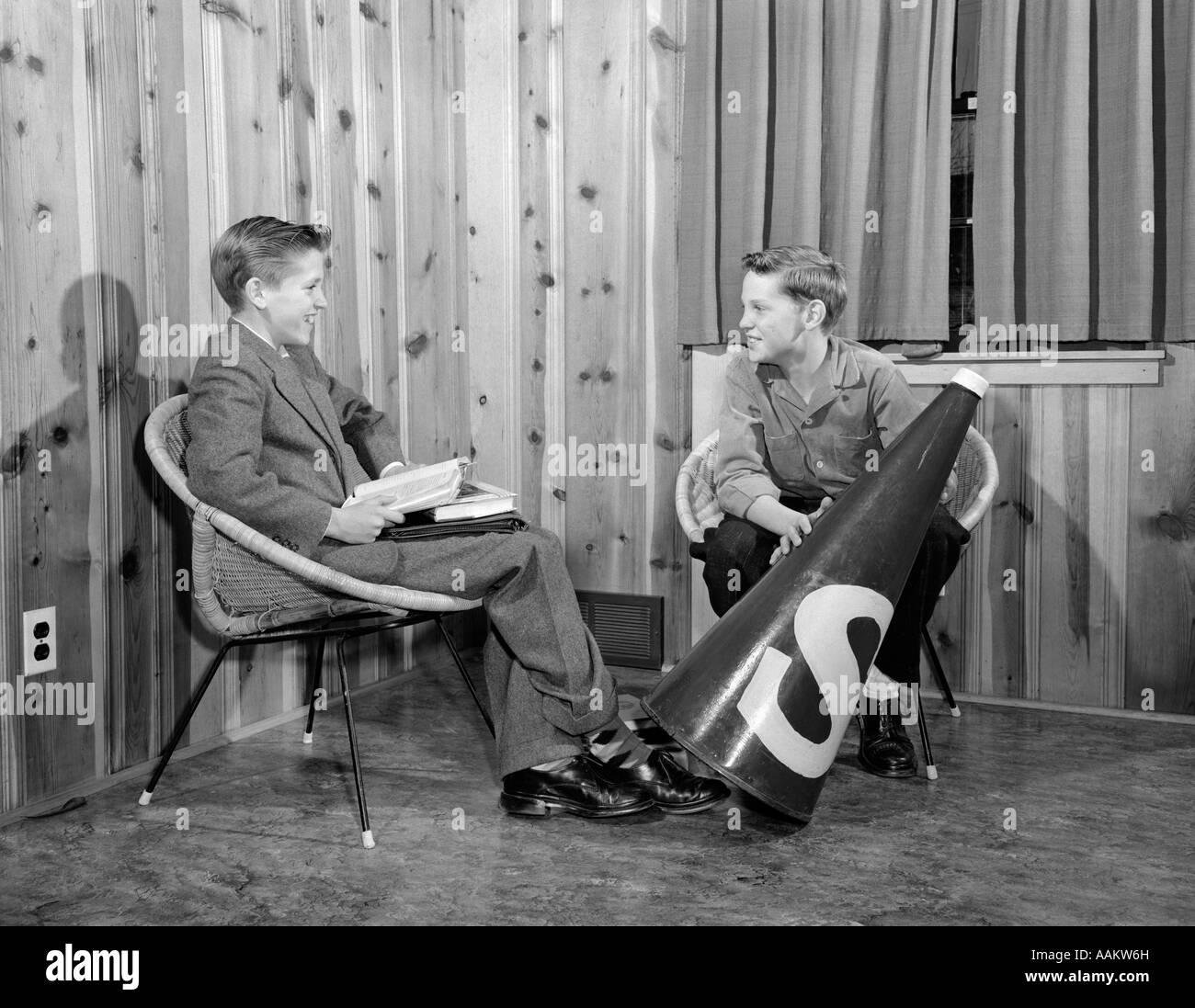 1950ER JAHREN ZWEI JUNGE TEEN-BOYS SITZEN STÜHLE SPRECHEN EIN JUNGE MIT GROßEN MEGAPHON Stockfoto