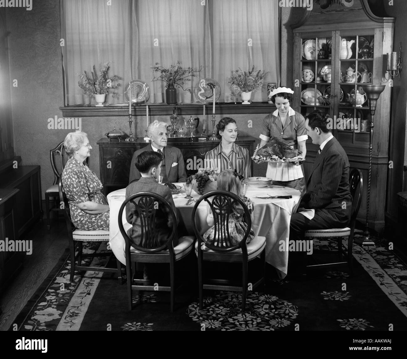 1940ER JAHREN ZWEI GENERATION FAMILIE IM SPEISESAAL THANKSGIVING-TRUTHAHN MIT MAID Stockfoto
