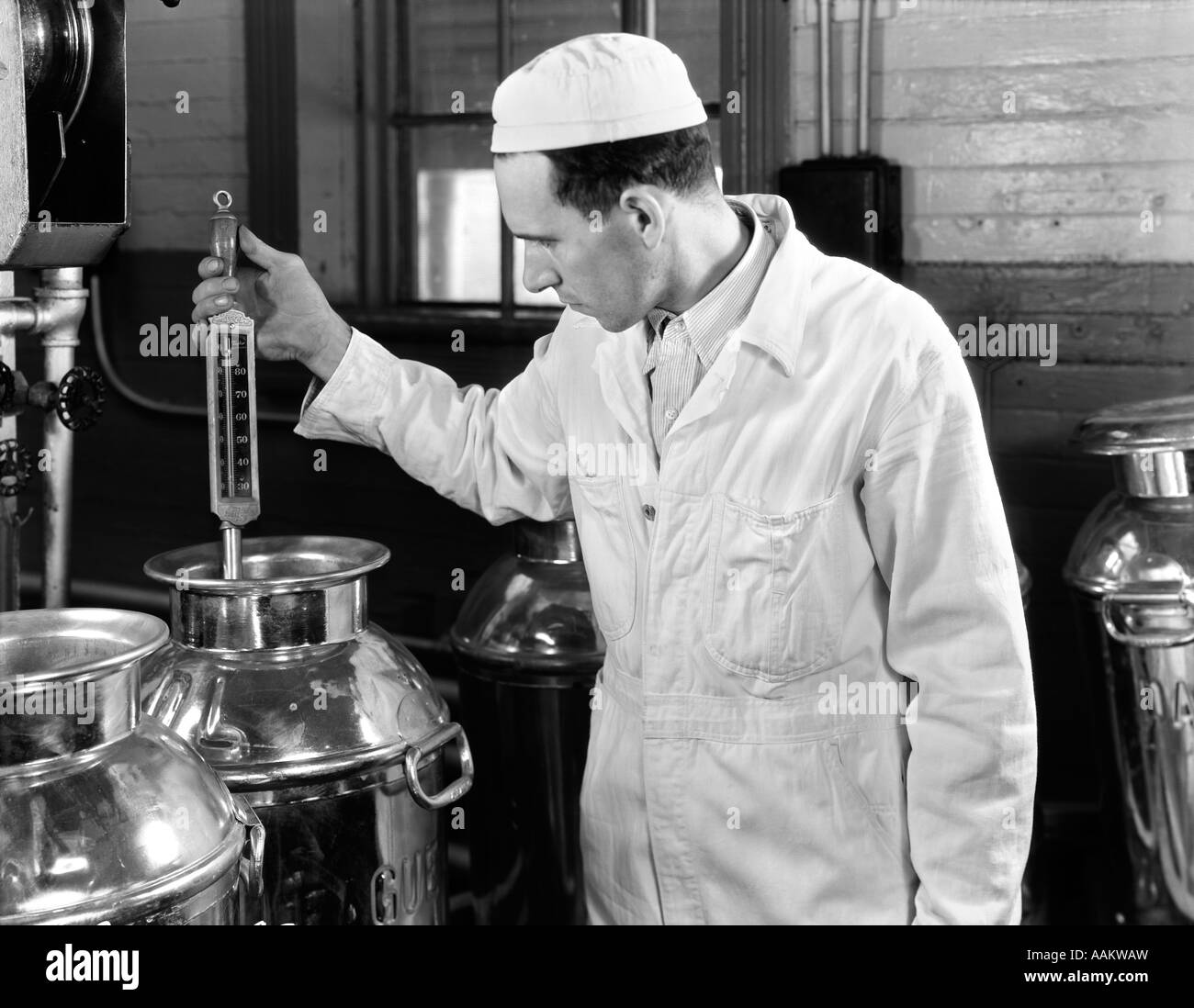 1930ER JAHRE SENNER TESTEN TEMPERATUR DER MILCH AN EINE MOLKEREI CO-OP Stockfoto