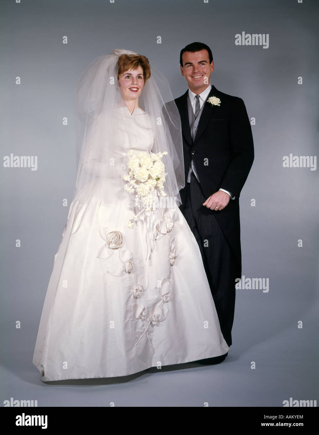 1960ER JAHREN FORMALE VOLLER LÄNGE STUDIOPORTRAIT VON BRAUT UND BRÄUTIGAM Stockfoto