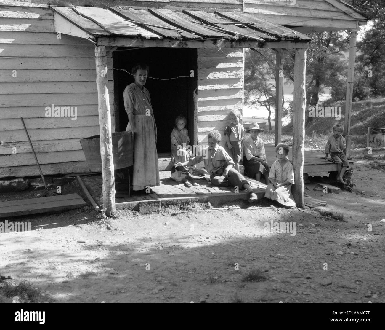 1930S 1940S BÄUERIN MIT SECHS KINDERN AUF VERANDA CLAP BOARD BAUERNHAUS Stockfoto