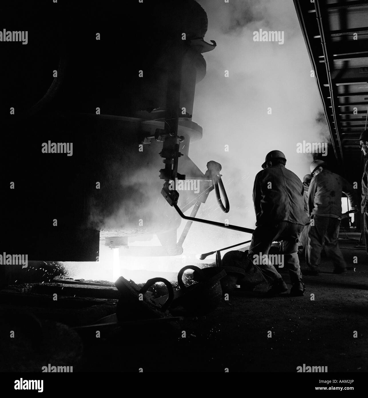 MÄNNER ARBEITEN IM STAHLWERK HOCHOFEN GESCHMOLZENE METALL HEIß HITZE SCHUTZHELM ARBEIT ALAN HOLZ STAHL Stockfoto