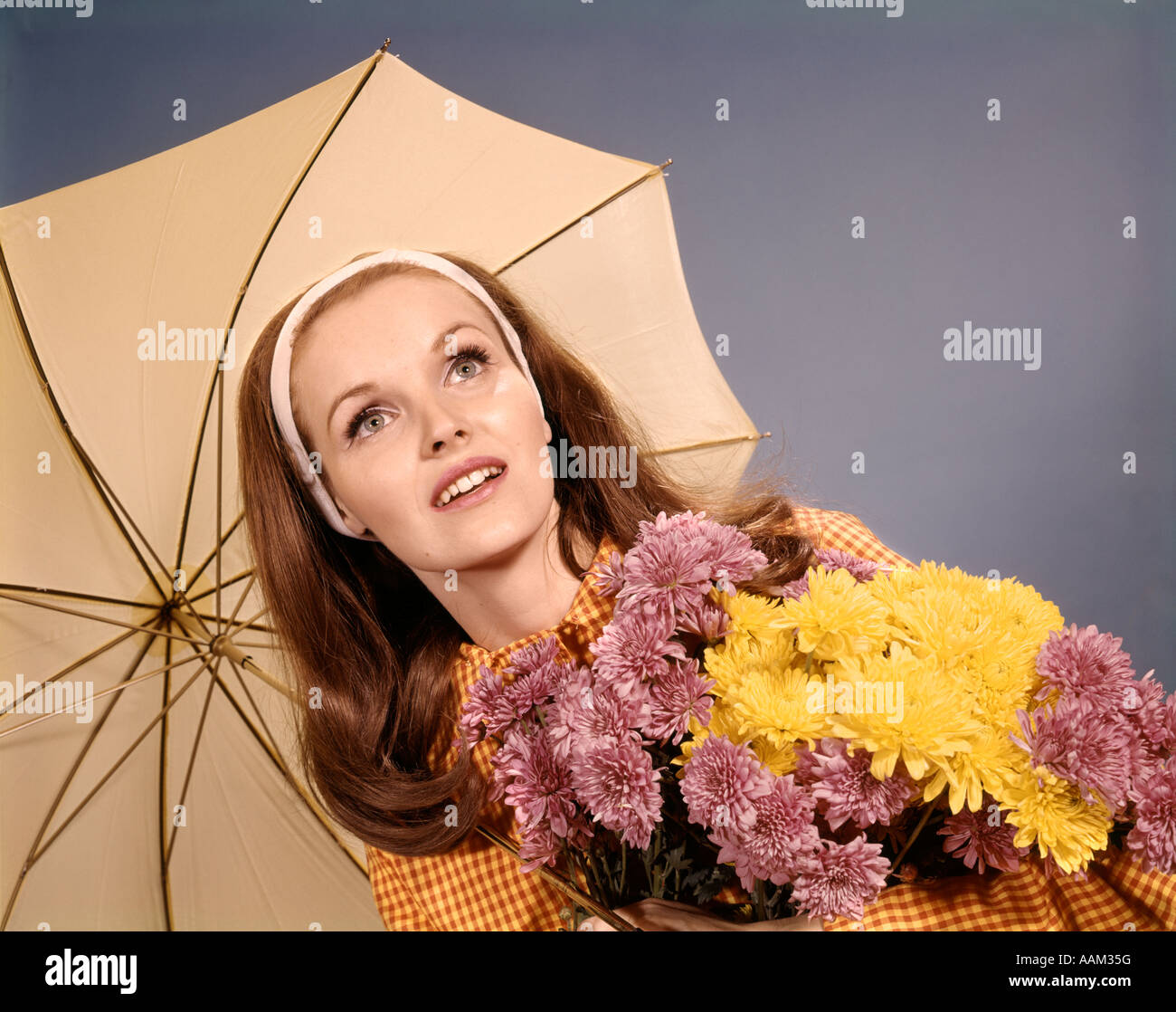 1960ER JAHREN FRAU ROTE HAARE HOLDING BLUMENSTRAUß UNTER DACH Stockfoto
