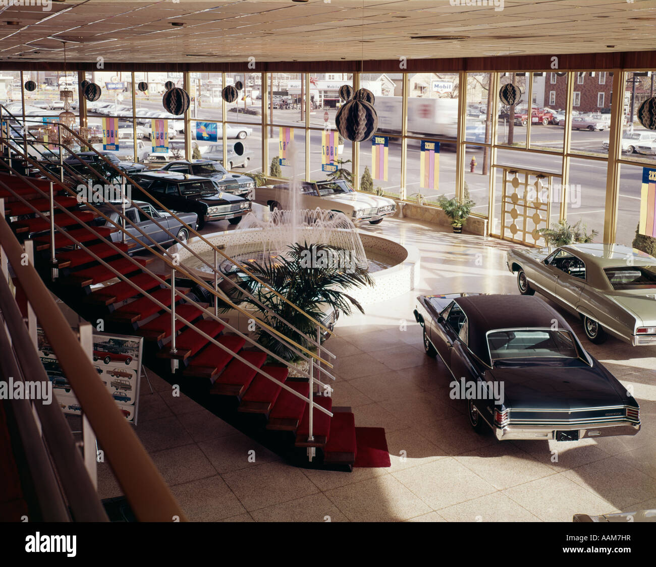 1960ER JAHREN INNENANSICHT DES AUTOMOBIL-SHOWROOM MIT GLASWÄNDEN UND ROTEN TEPPICH AUF TREPPE Stockfoto