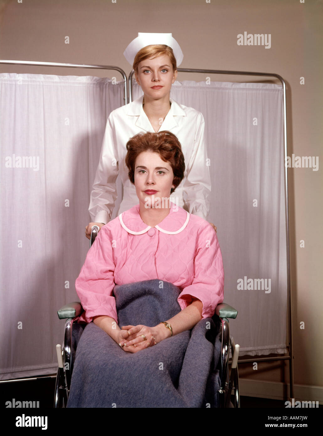 1960 1960S FRAU ERNSTEN AUSDRUCK IM ROLLSTUHL WEIBLICH KRANKENSCHWESTER SCHOB STUHL KRANKENHAUS KRANKENPFLEGE PATIENTEN MEDIZINISCHE Stockfoto