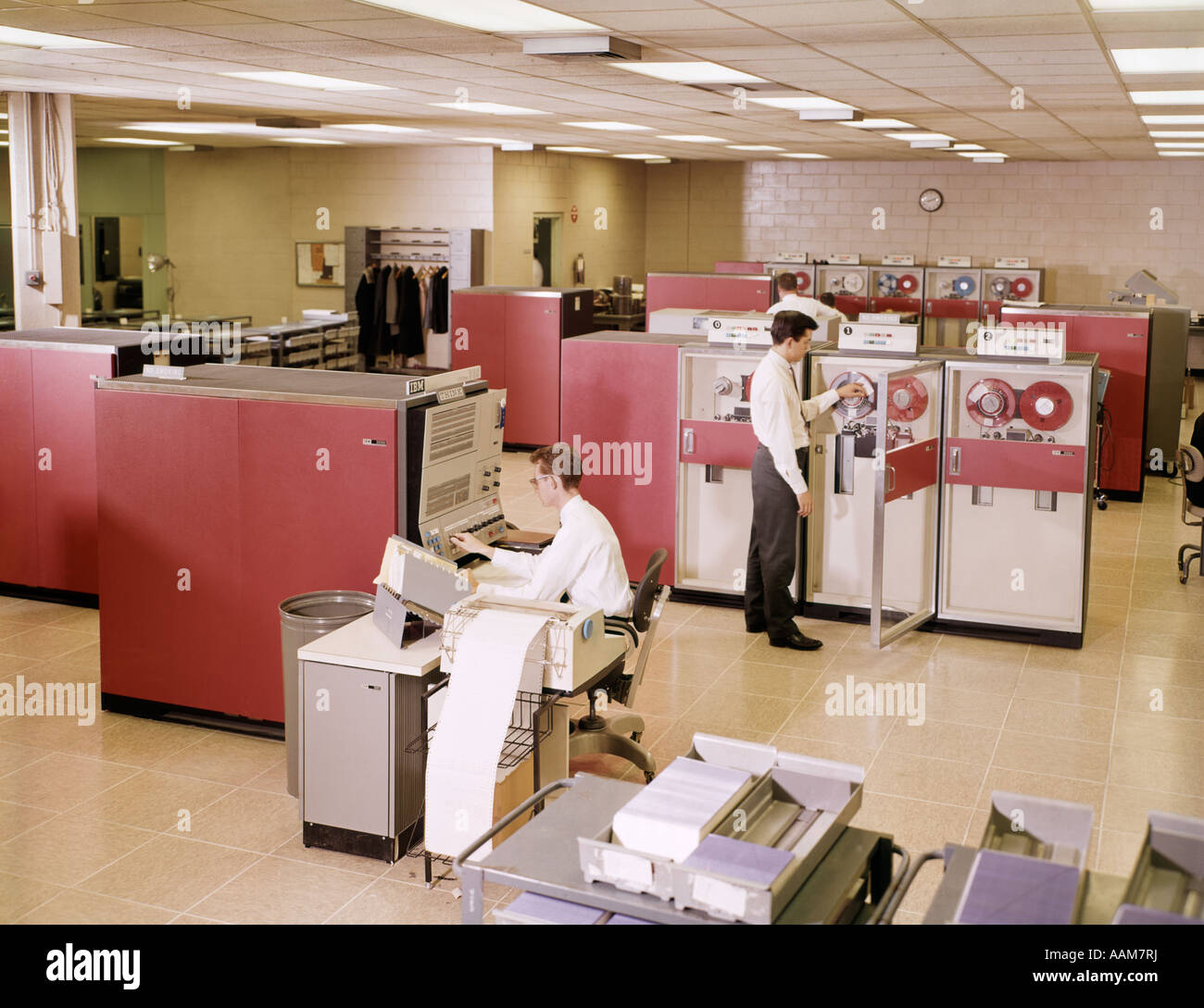 1960ER JAHRE ZWEI MÄNNER IM BÜRO ARBEITEN BEI MAINFRAME REEL TO REEL COMPUTER Stockfoto
