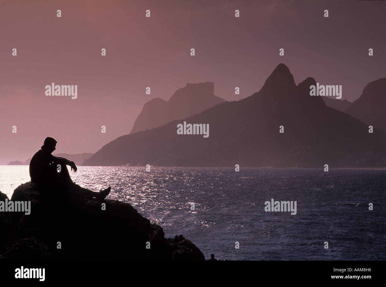 Sonnenuntergang am Ipanema Strand Rio de Janeiro Brasilien nachdenklich nachdenklicher Mann Sitted in Arpoador Steinen Stockfoto