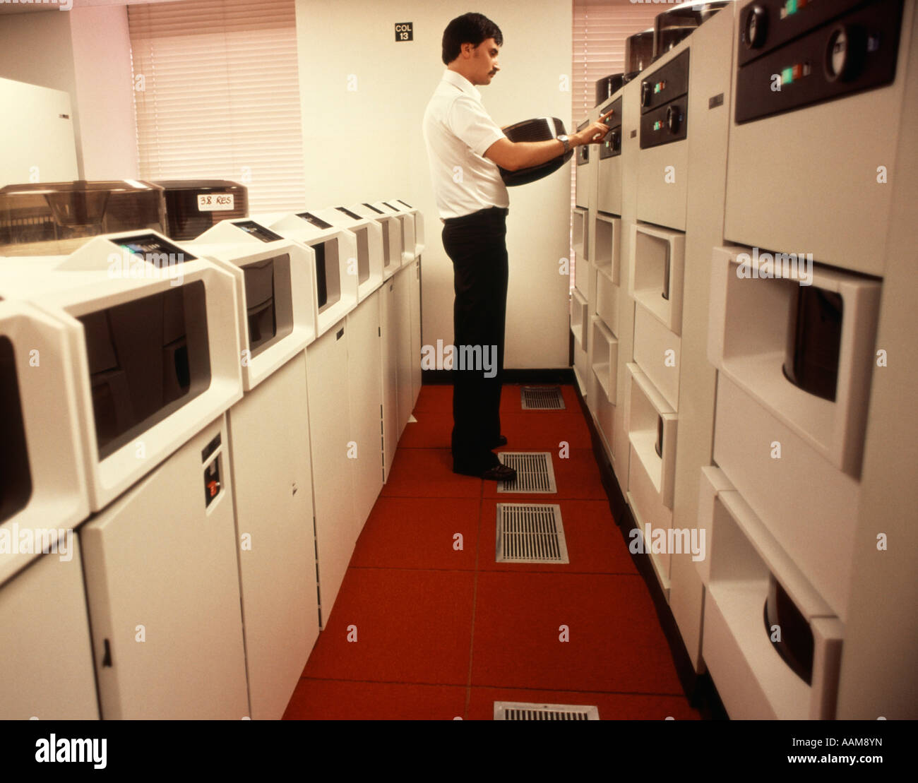 1970S 1980S COMPUTER-TECHNIKER ÄNDERUNG REEL AUF MAIN FRAM COMPUTER ROT & WHITE ROOM Stockfoto