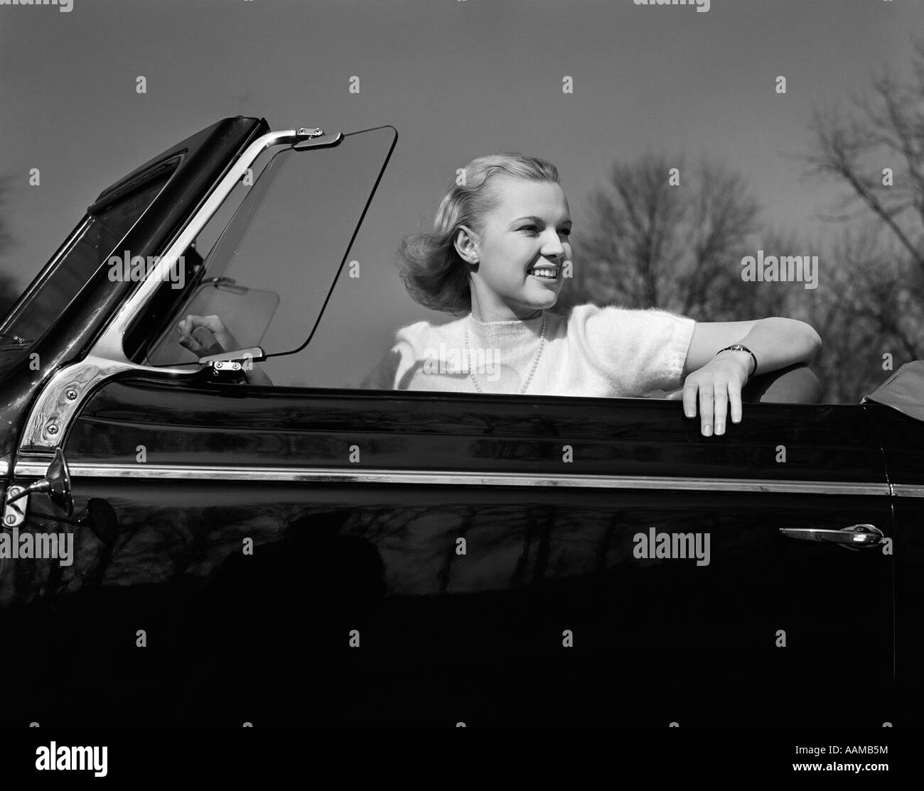 1930S 1940S LÄCHELND HÜBSCHE BLONDE TEENAGER FRAU IM CABRIO AUTO FAHRERSITZ Stockfoto