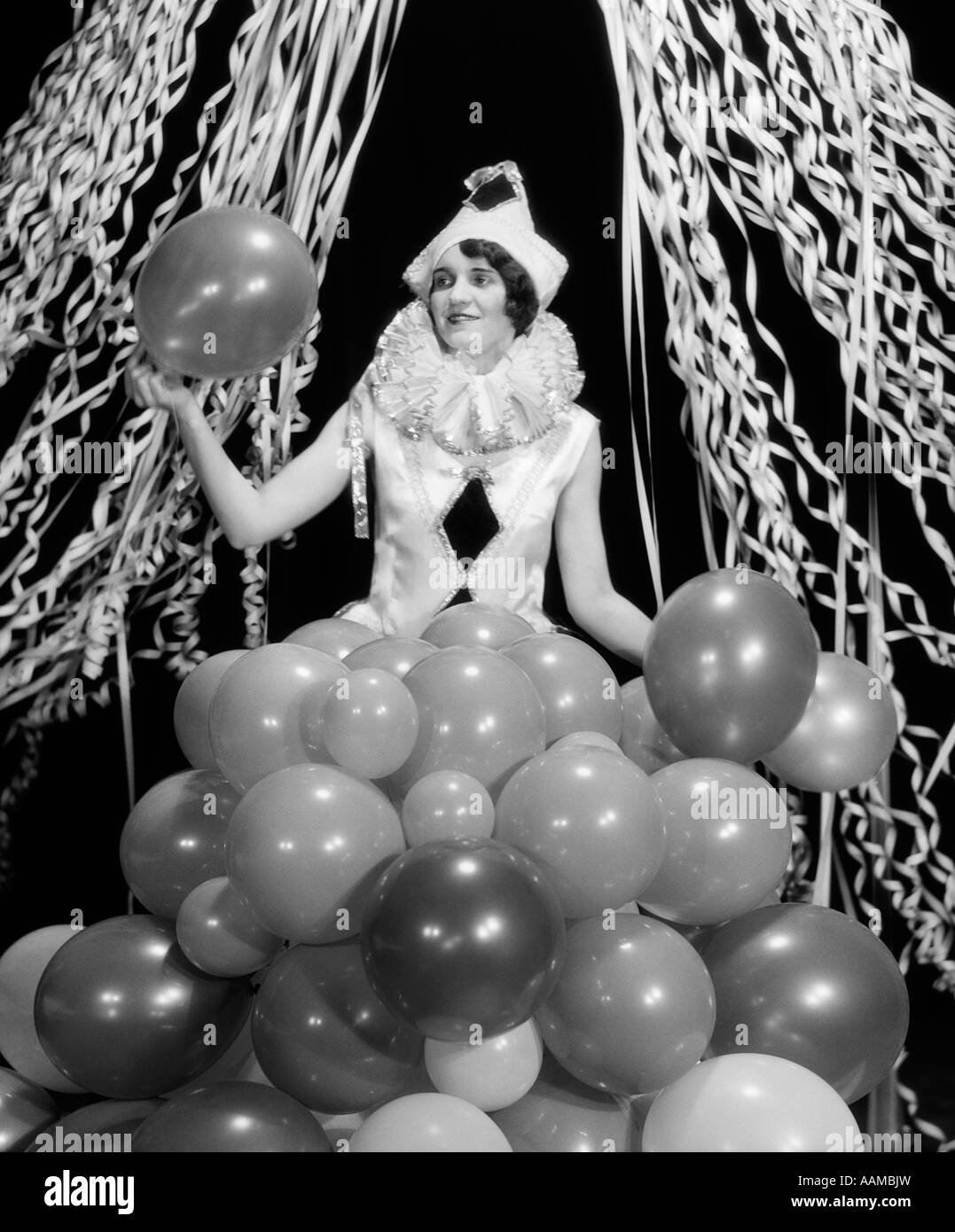 1920s 1930s lächelnde junge Frau Pierrot CLOWN PARTY LUFTBALLONS und Luftschlangen Stockfoto