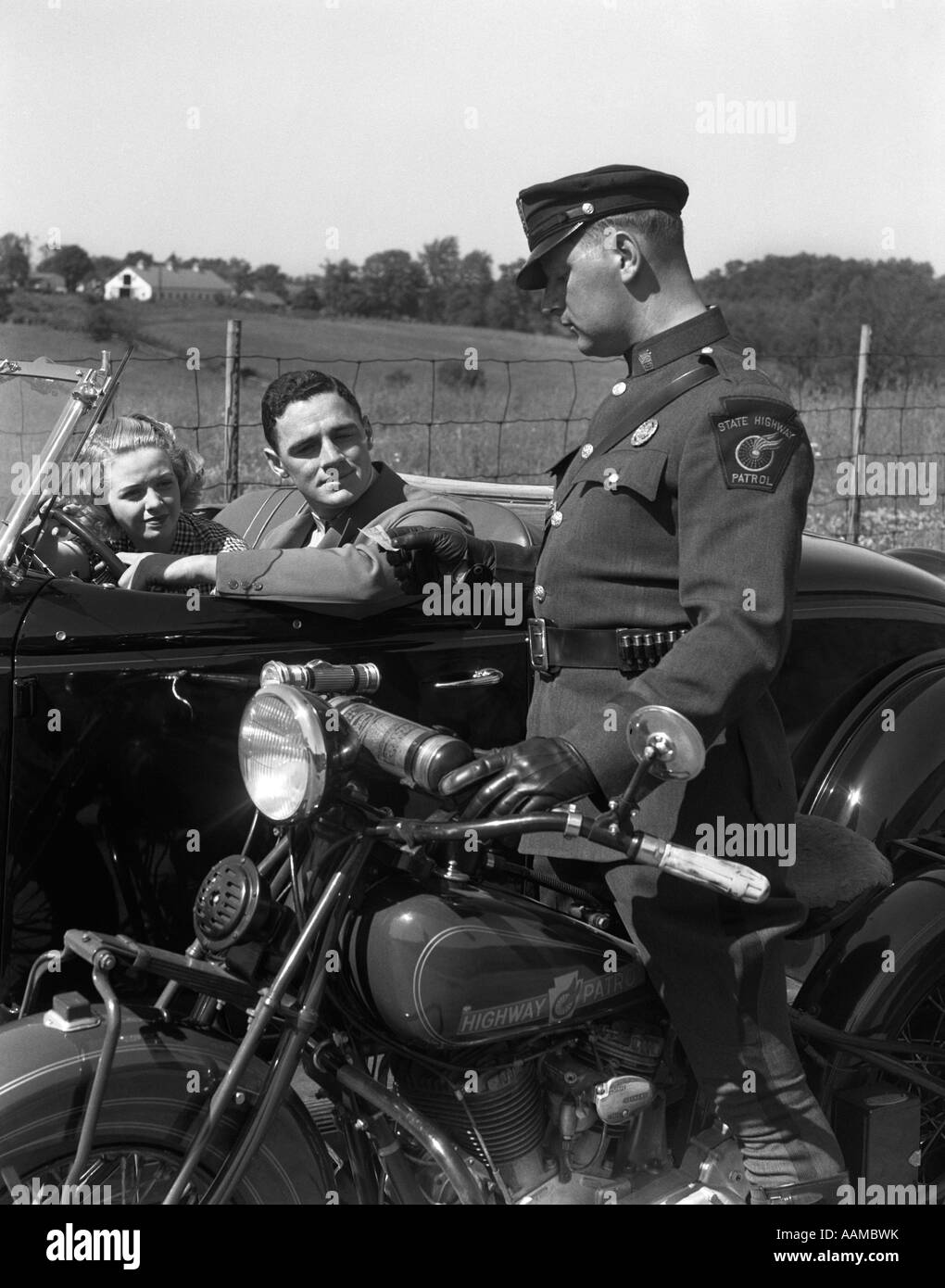 1930ER JAHREN PAAR IM CABRIO COUPE VON COP PRÜFUNG MOTORRADFÜHRERSCHEIN FAHRER GESTOPPT Stockfoto