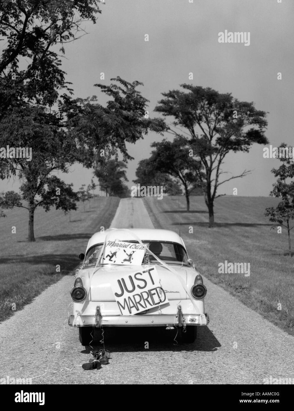 RÜCKSEITE DES WEIßEN FORD SEDAN ANFAHREN MIT JUST MARRIED ZEICHEN DER 1950ER JAHRE AUF STAMM Stockfoto