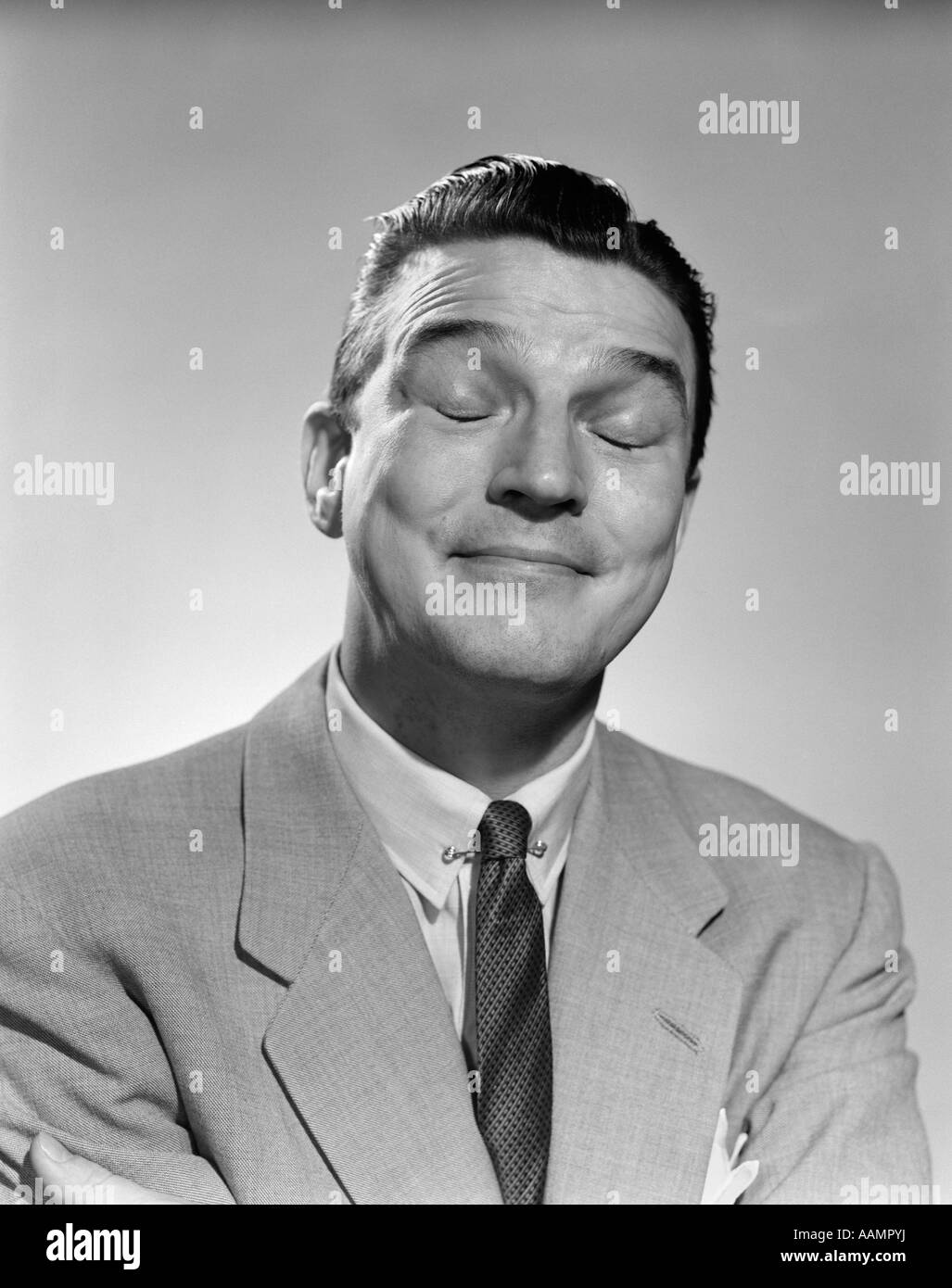1950ER JAHRE MANN LACHENDEN AUGEN GESCHLOSSEN DENKEN NACHDENKLICH ENTSPANNT RIECHEN LUSTIGE MIMIK Stockfoto