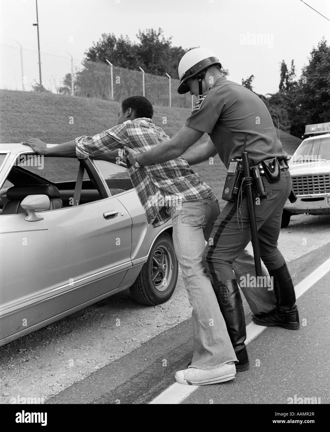 1970ER JAHREN VERBREITEN POLIZIST SUCHE AFRIKANISCHE AMERIKANER EAGLE GEGEN AUTO Stockfoto