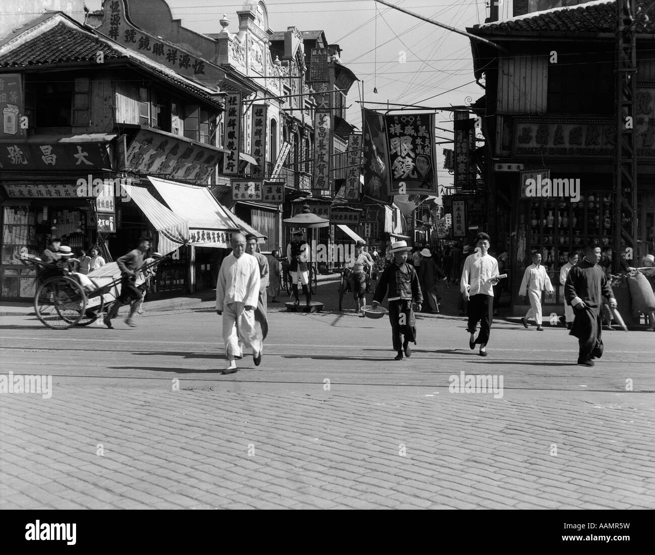 1920S 1930S TYPISCHE STRAßENSZENE IN SHANGHAI CHINA FUßGÄNGER MENSCHEN GESCHÄFTE RIKSCHA TAGSÜBER Stockfoto