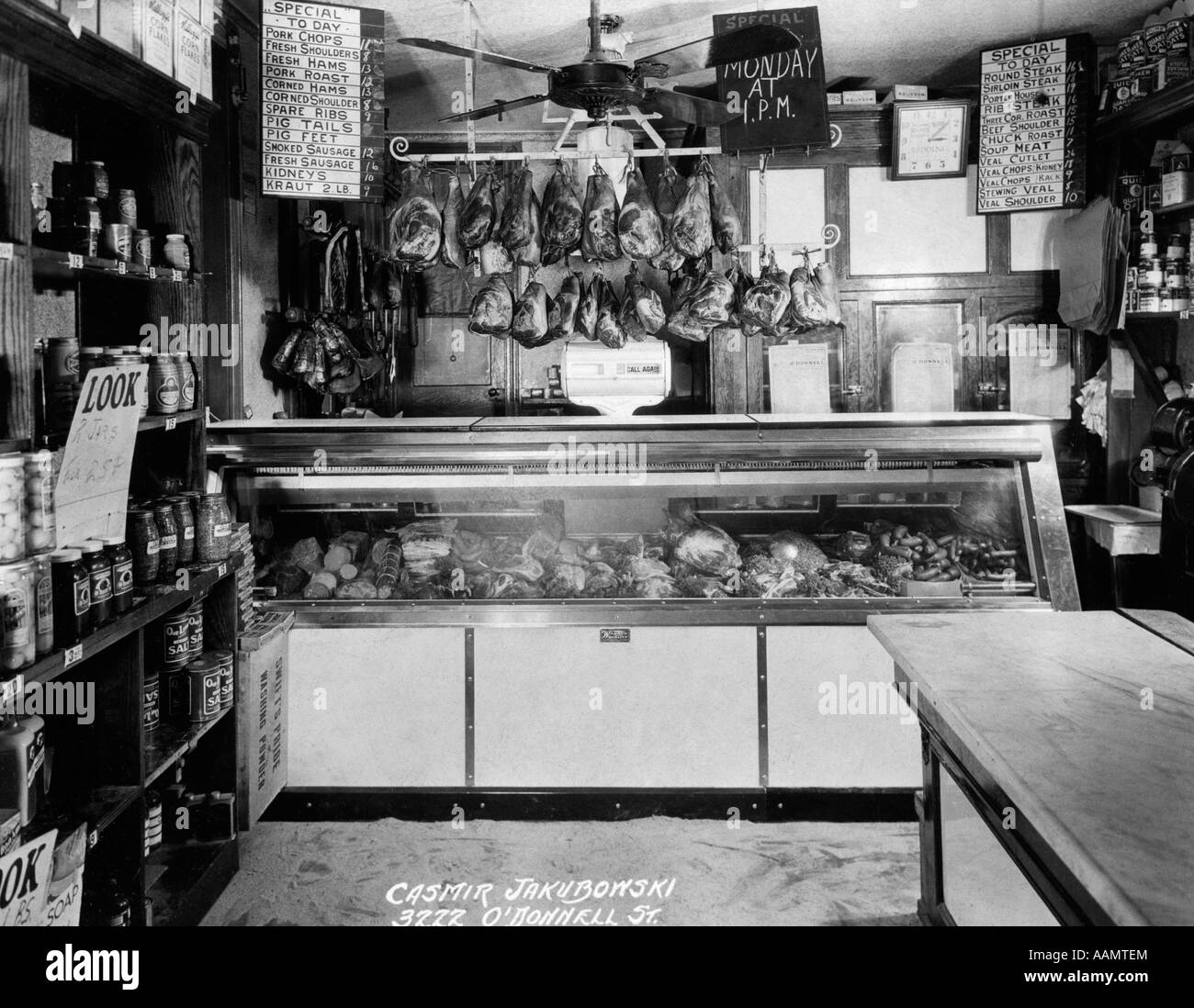 OLD-TIME METZGER VITRINE MIT FLEISCH HÄNGEN RACK OBEN IM KLEINEN SUPERMARKT Stockfoto