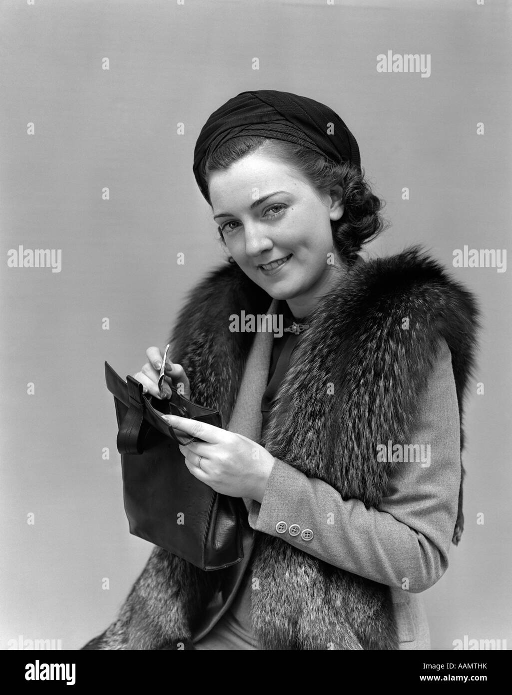 1930S 1940S FRAU VERKLEIDET MIT PELZJACKE GELDBÖRSE UND GELD BLICK IN DIE KAMERA HALTEN Stockfoto