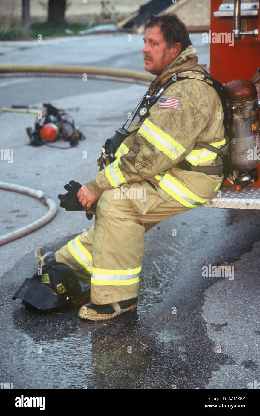 Erschöpft Feuerwehrmann sitzt auf der Rückseite des Feuer LKW ruhen Stockfoto