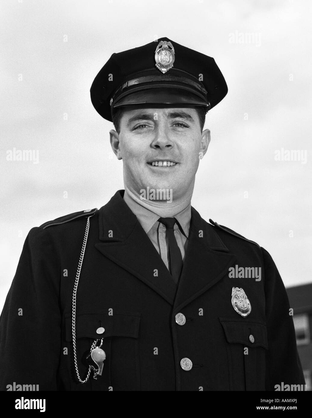 1960ER JAHRE PORTRAIT HÜFTE AUFWÄRTS LACHENDE POLIZIST Stockfoto