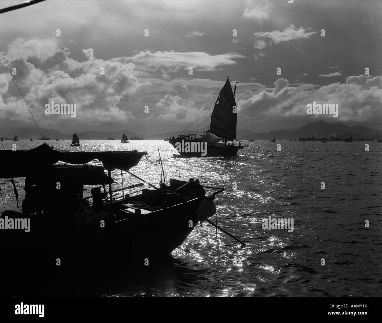 1920S 1930S DRAMATISCHEN SONNENUNTERGANG HAFEN MIT SILHOUETTE CHINESISCHE DSCHUNKEN UND BOOTE-HONG KONG-CHINA Stockfoto