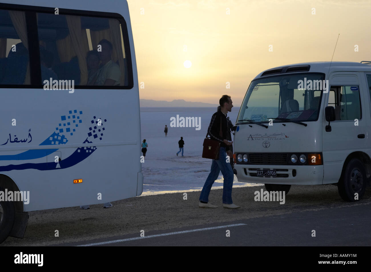 Tourist bewegt sich zwischen zwei Reisebusse beim Sonnenaufgang über Chott el Djerid Tunesien Stockfoto