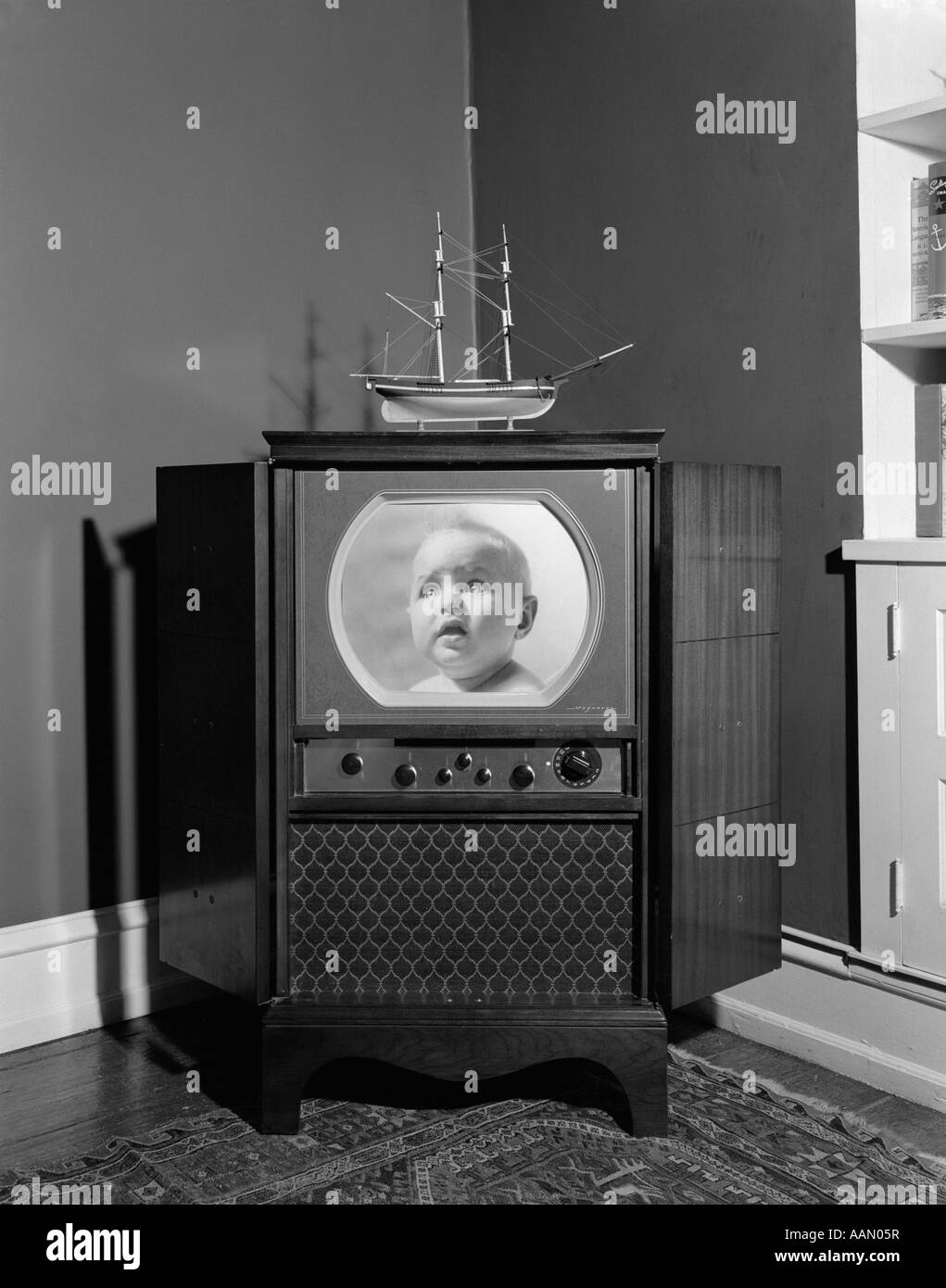 1940S 1950S KONSOLE SCHWARZ / WEIß FERNSEHER MIT VIELEN ZIFFERBLÄTTER KNÖPFE INNENRAUM MIT MODELLSCHIFF UND ORIENTTEPPICH Stockfoto