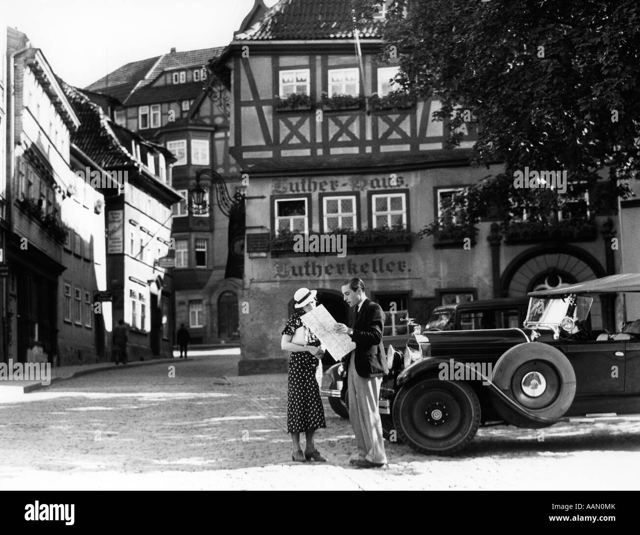 1930ER JAHRE TOURIST PAAR MIT DEM AUTO, MIT BLICK AUF DIE LANDKARTE VOR EISENACH LUTHERHAUS 1563 WO LUTHER LEBTE WÄHREND SCHULE BESUCHEN Stockfoto