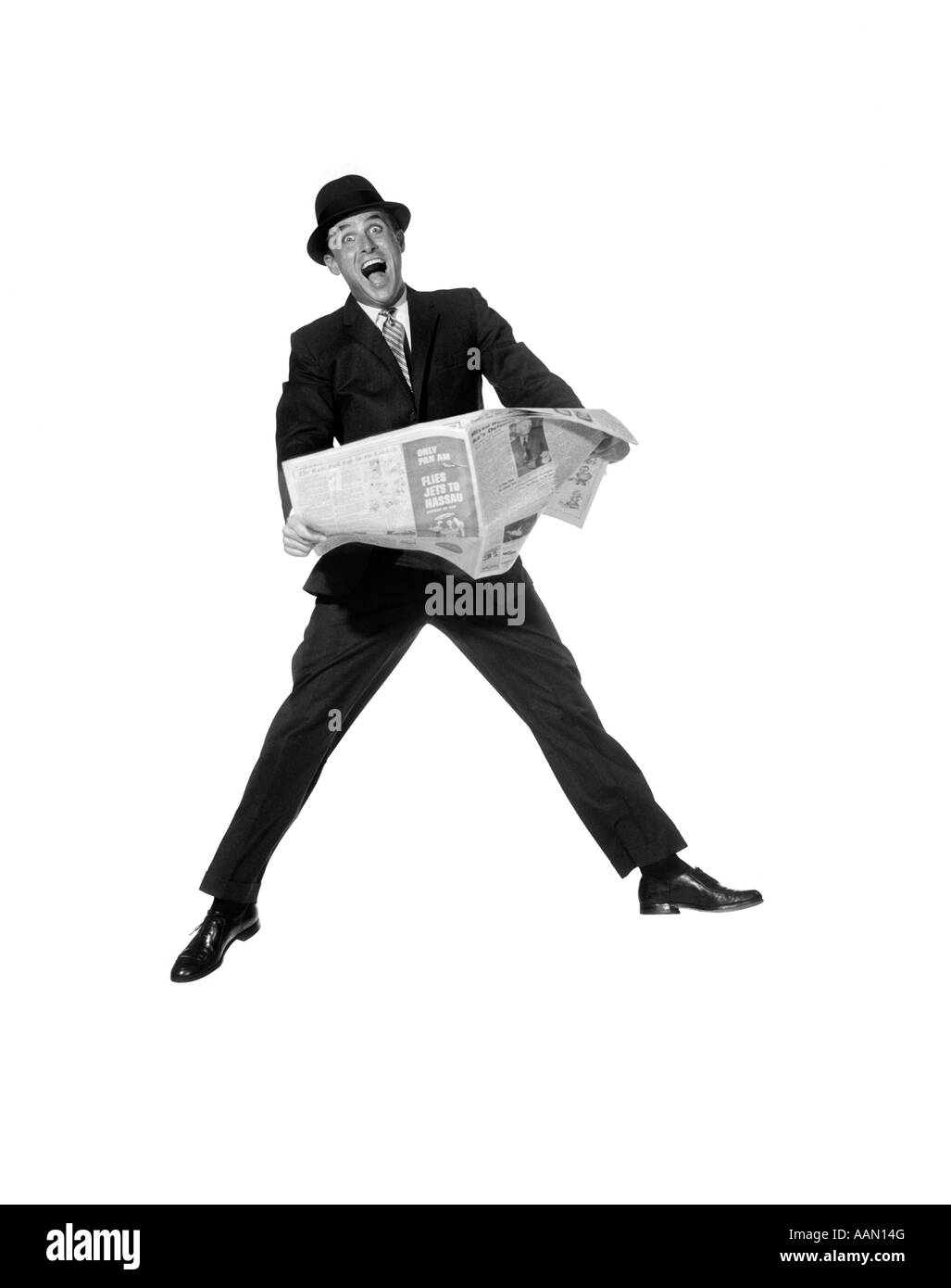 1950ER JAHRE MANN IN ANZUG UND HUT HOLDING ZEITUNG MIT ÜBERTRIEBENER AUSDRUCK Stockfoto