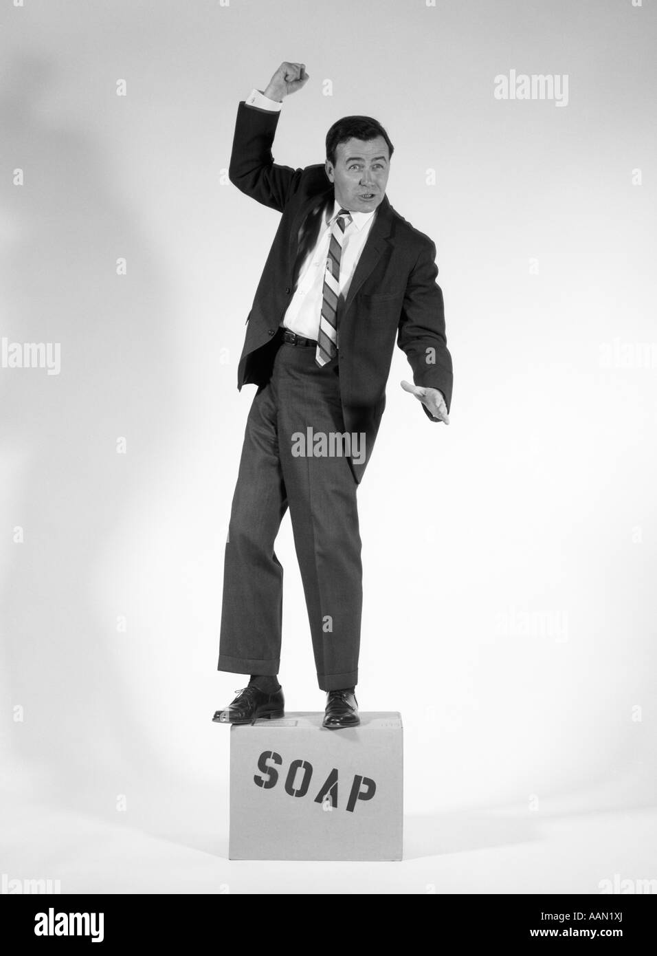 1960ER JAHREN BÖSE MANN IM ANZUG AUF SEIFENKISTE Stockfoto