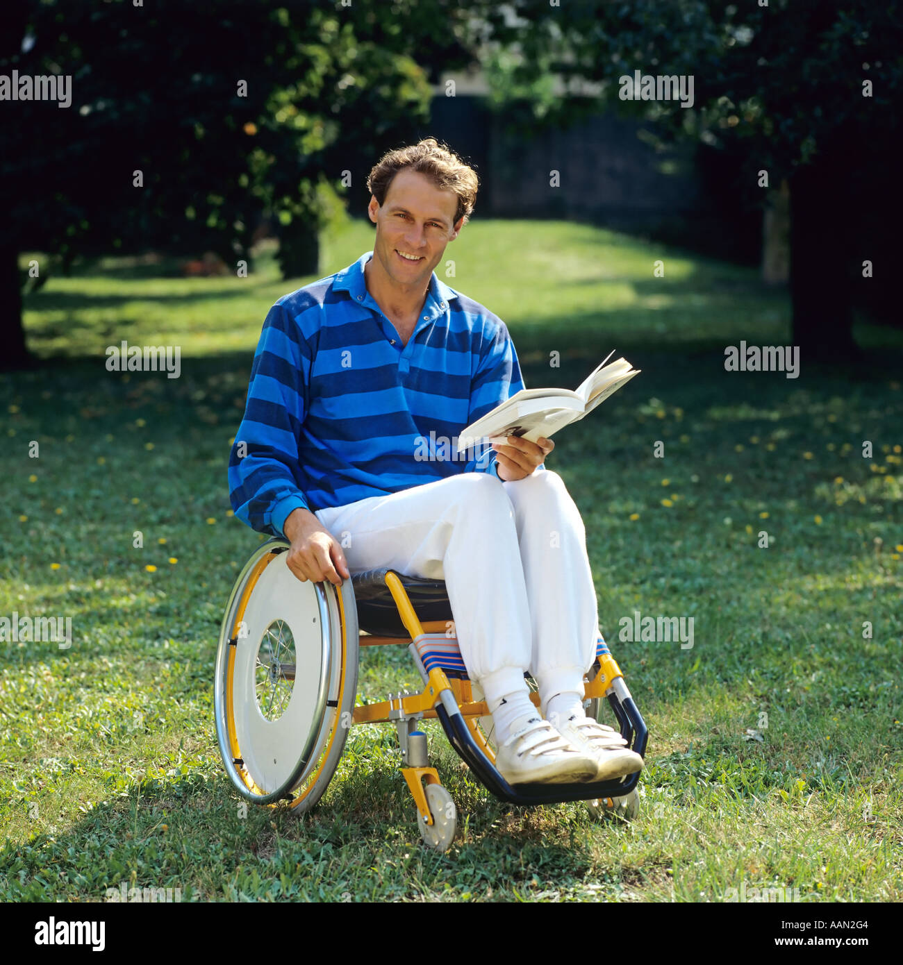 Behinderte Mensch mit Buch im Rollstuhl im Garten Stockfoto