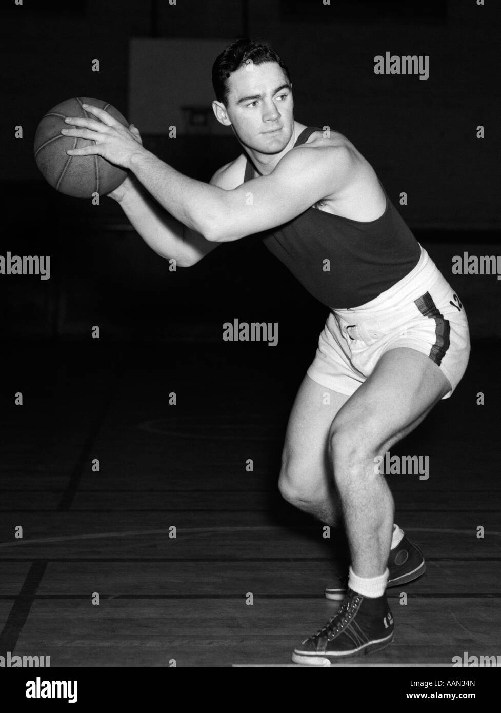 1930ER JAHRE TEEN JUNGEN SPIELEN BASKETBALL HOLDING BALL STEHEN IN POSITION Stockfoto