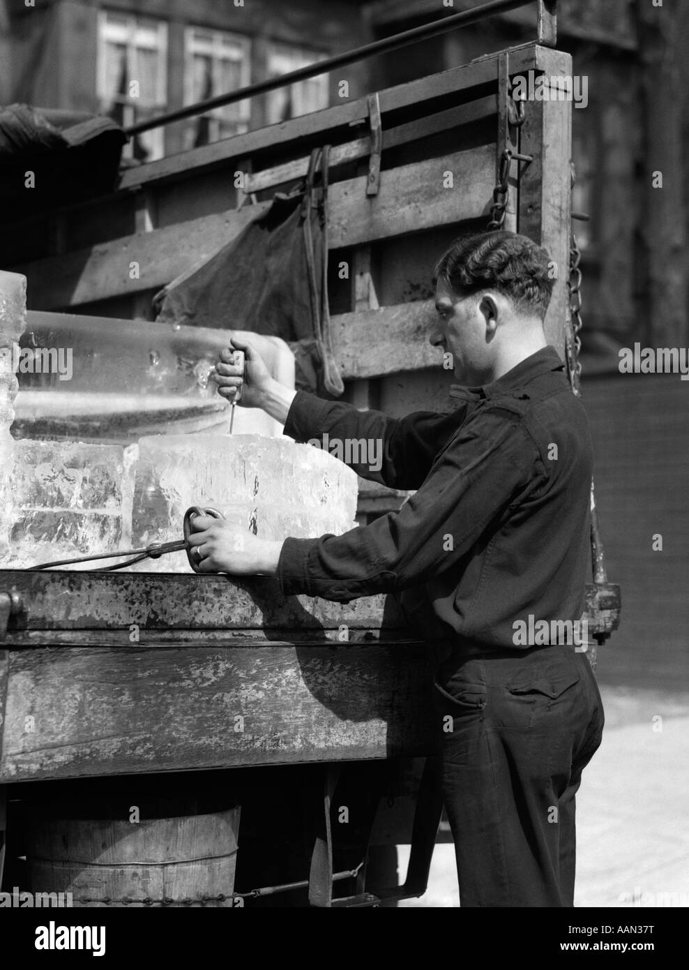 1930ER JAHREN EIS LIEFERUNG MANN AT RÜCKSEITE DES LKW MIT ZANGE IN DER HAND & PUTTING EISPICKEL IN EIS MIT ANDEREN BLOCKIEREN Stockfoto