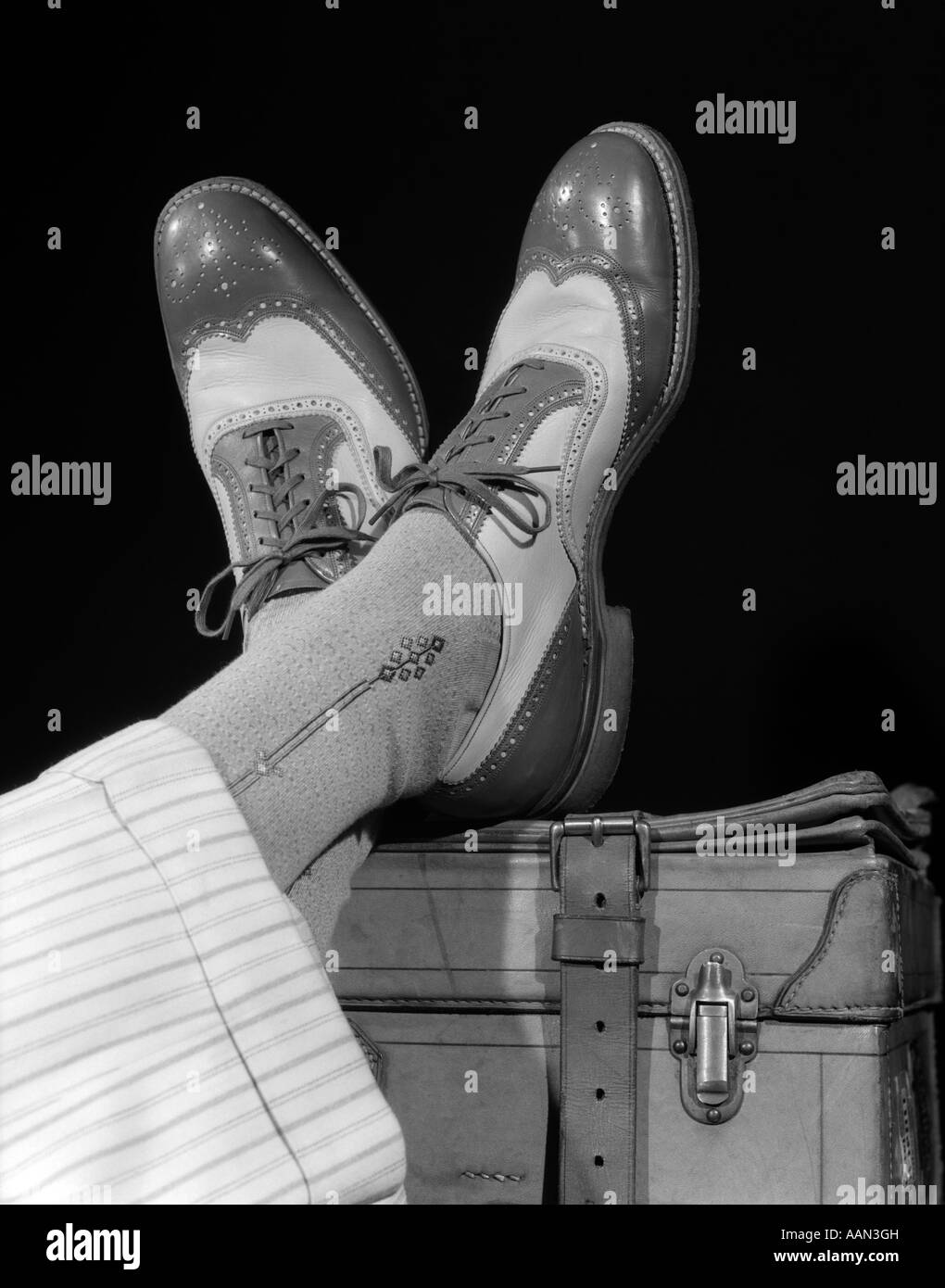 1930S 1940S GEKREUZTE FÜßE EINES MANNES TRAGEN TWO TONE FLÜGELS SPECTATOR SCHUHE SEIDE SOCKEN UND GESTREIFTE WEIßE WOLLE SPITZE CUFFED HOSE Stockfoto