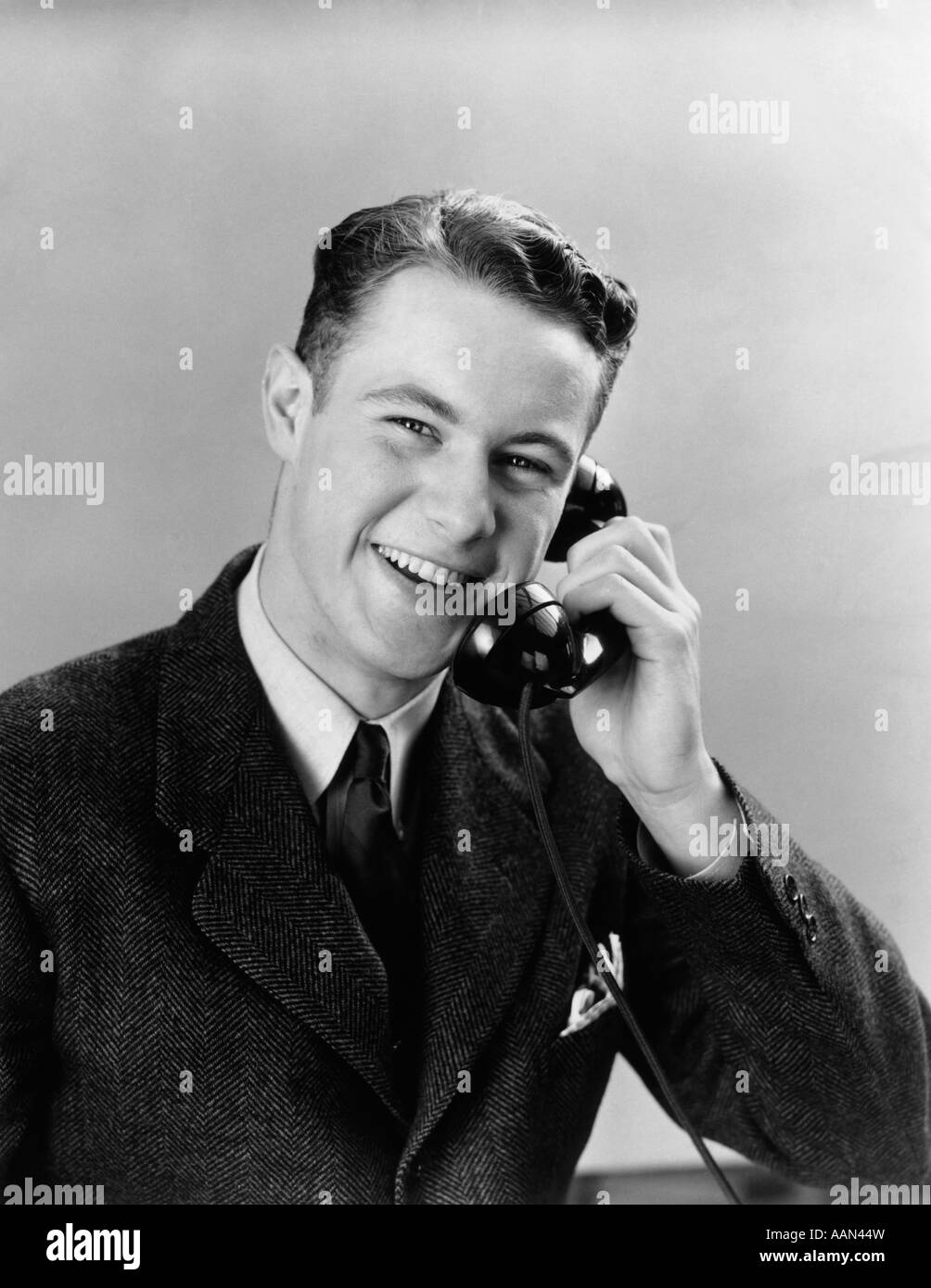 1940S 1950S JUNGER MANN AM TELEFON, BLICK IN DIE KAMERA SPRECHEN Stockfoto