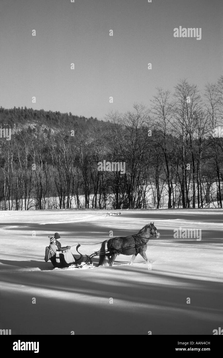 1970ER JAHREN PAAR REITEN IN CUTTER SCHLITTEN HINTER EINEM EINZIGEN PFERD IN KNIE TIEFSCHNEE NORTH CONWAY VERMONT USA Stockfoto