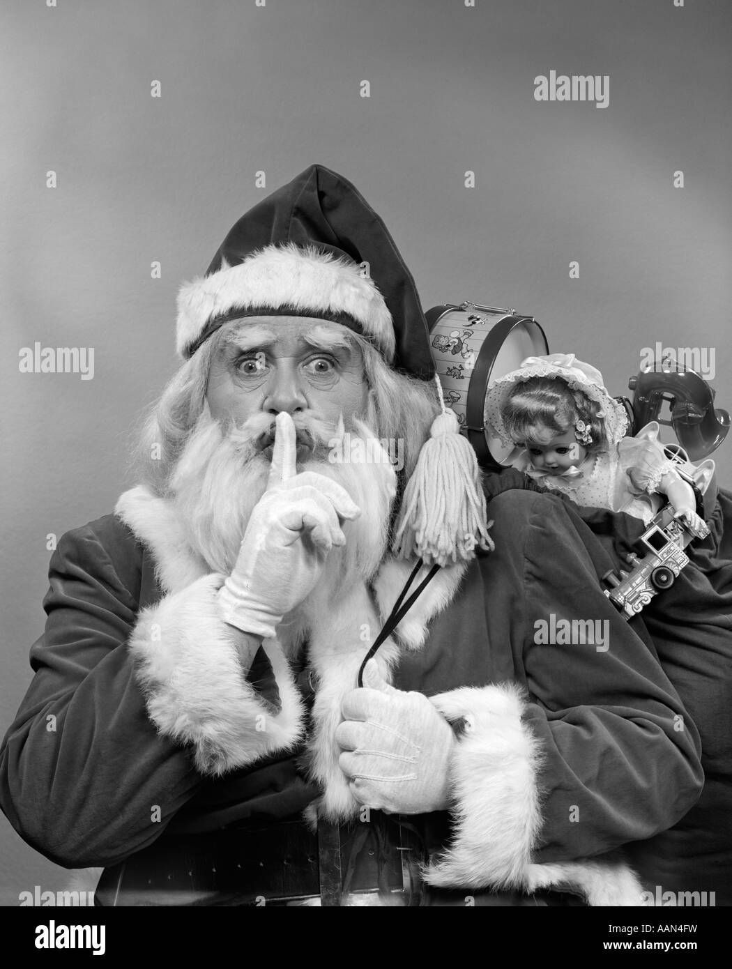 1950ER JAHREN WEIHNACHTSMANN MIT EINER TASCHE VON SPIELZEUG MACHEN GESTE BLICK IN DIE KAMERA STILL Stockfoto